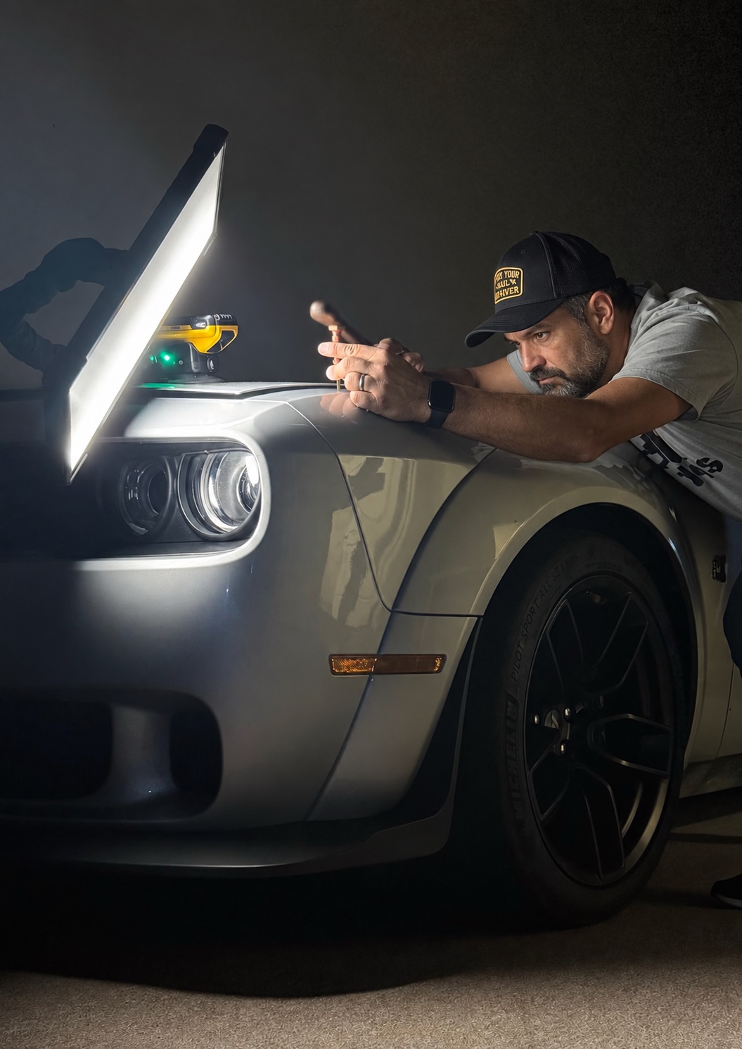 Paintless dent repair technician using a reflection inspection light on a vehicle