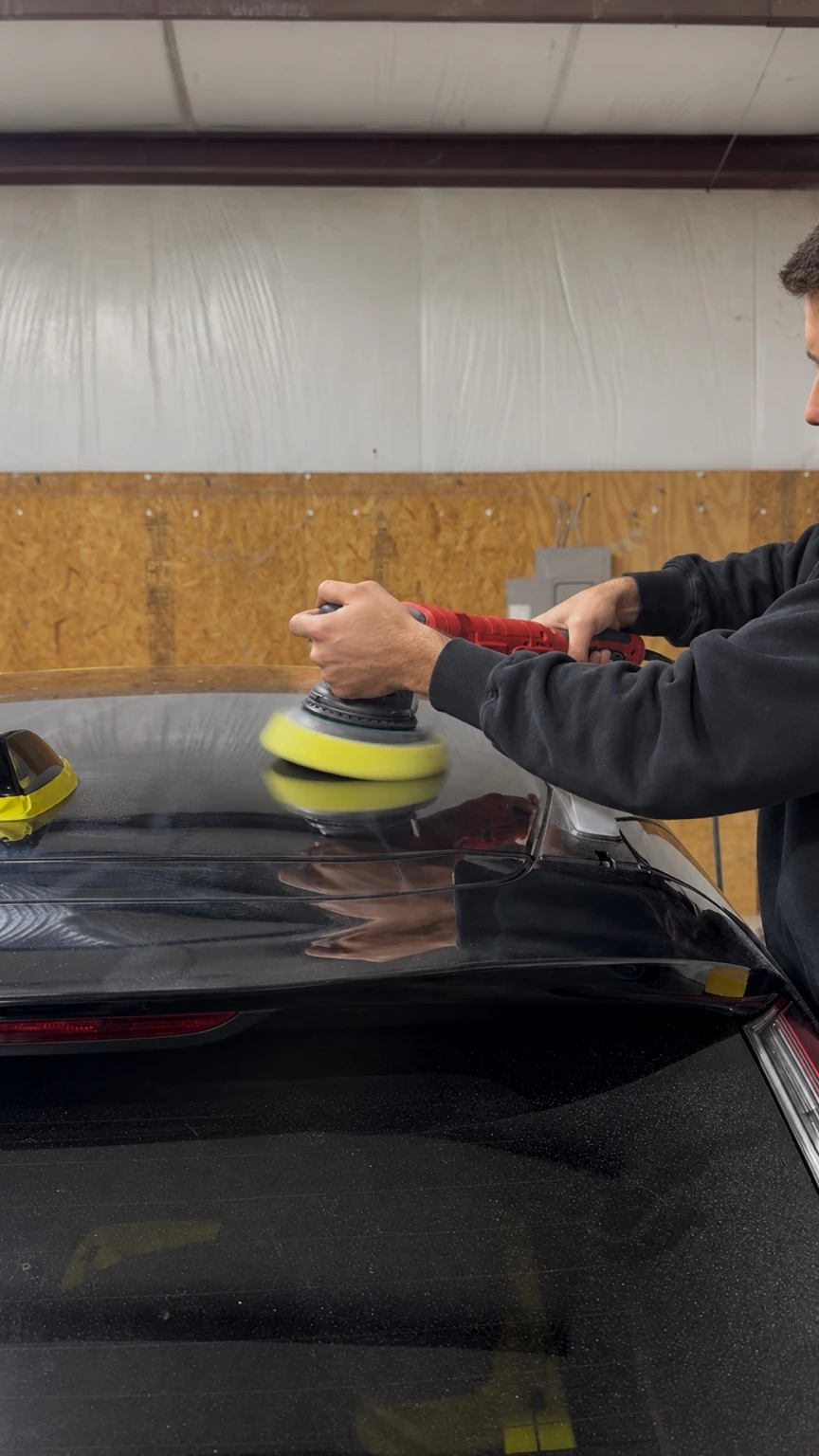 Real automotive paint polishing in progress on the roof of a black vehicle